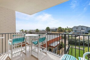 Un balcone con tavolo e sedie, con vista su una zona residenziale e un corso d'acqua.