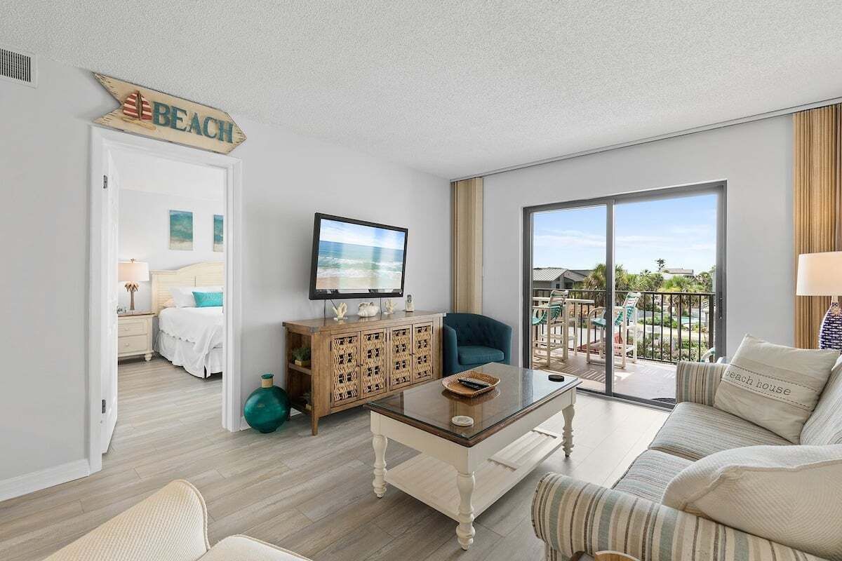 A hotel room with a balcony, a television, a sofa, and a bed.