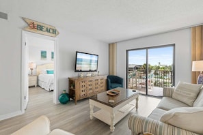 Une chambre d’hôtel avec un balcon, une télévision, un canapé et un lit.