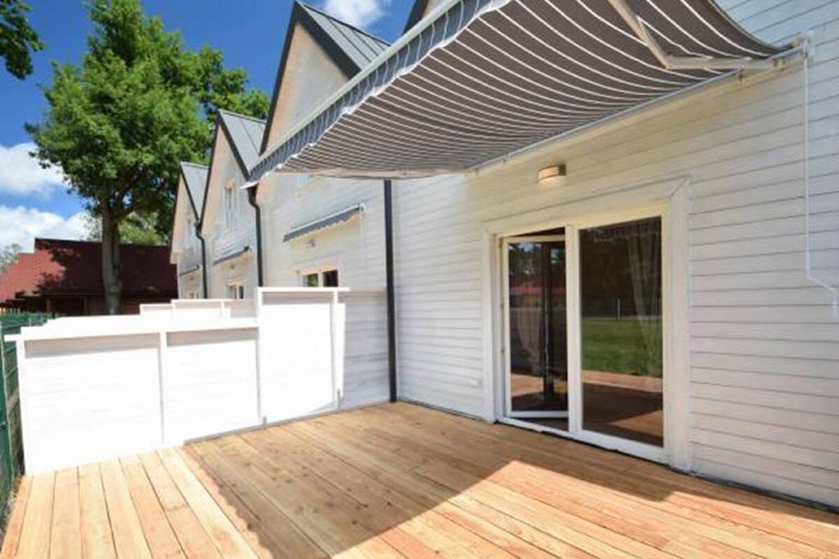 Ein modernes Haus mit Holzterrasse, weißen Außenwänden und einer überdachten Veranda.