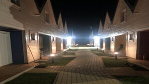 A pathway leading to a row of hotel rooms with a central lawn area. - TuNa (Dziwnów)