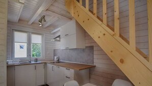 A kitchen with white cabinets, a wooden countertop, and a wooden staircase. - TuNa (Dziwnów)