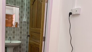 A bathroom with a wooden door, a white sink, and a mirror. - Rendezvous Inn (Mandalay)