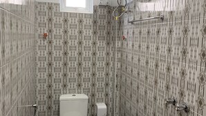 A small bathroom with a toilet, a shower, and a window. - Rendezvous Inn (Mandalay)