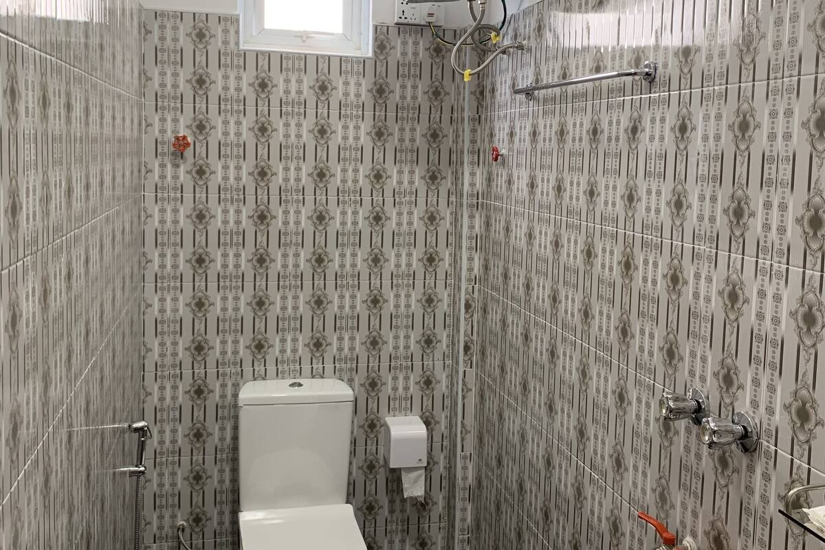 A small bathroom with a toilet, a shower, and a window.
