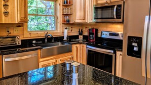 A modern kitchen with wooden cabinets, a built-in oven, a microwave, a coffee maker, and a water dispenser.