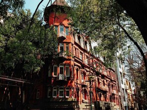Un edificio in mattoni rossi con numerose finestre e balconi, immerso nel verde.
