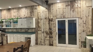 A kitchen with wooden panel walls, white cabinets, and a dining area with a wooden table and chairs. - Private country setting with large indoor pool (Virden)