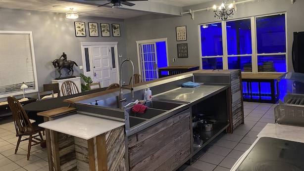 A modern kitchen with a central island, wooden cabinetry, and a dining area with chairs. - Private country setting with large indoor pool (Virden)