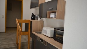 Eine kleine Küche mit Holzstuhl, Mikrowelle, Toaster und Kaffeemaschine.