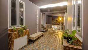 Un pasillo con piso a cuadros, un banco y plantas en macetas.