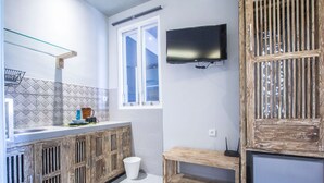 Una cocina moderna con salpicadero de azulejos, armarios de madera, una ventana y un televisor montado.