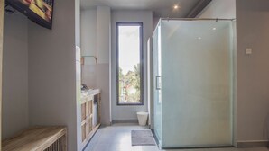 Et moderne badeværelse med en glasbrusekabine, et spejl med vask og et vindue med udsigt.