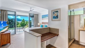 A modern hotel room with a large balcony, a ceiling fan, a bed with a view, a small desk, and a shower area. - Frangipani 8 - ground floor apartment (Hamilton Island)