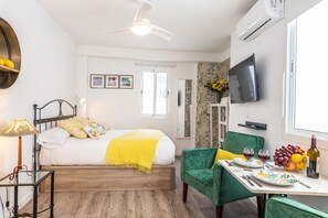A bedroom with a bed, bedside table, lamp, and a TV on the wall.