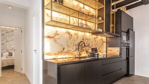 A modern kitchen with a marble backsplash, black cabinetry, and built-in shelves.