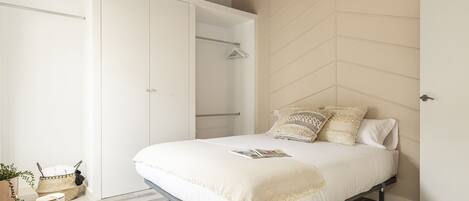 A bedroom with a bed, bedside table, and a wardrobe.