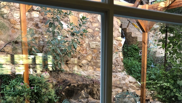 A wooden deck with metal chairs and a table, surrounded by stone walls and greenery. - 2-story house, all the comforts of home, spectacular space and views!! (Bisbee)