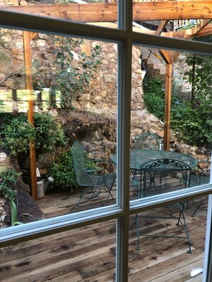 A wooden deck with metal chairs and a table, surrounded by stone walls and greenery. - 2-story house, all the comforts of home, spectacular space and views!! (Bisbee)