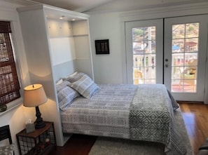 Une chambre à coucher avec un lit, une lampe de chevet, une fenêtre et une porte.