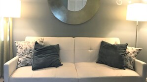 A white sofa with two pillows, a decorative wall hanging, and two lamps. - Relax in Your Own Private Suite in Charleston's James Island! (Charleston)