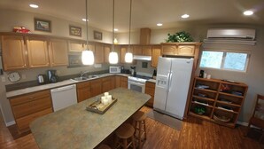 A modern kitchen with wooden cabinets, a central island, stainless steel appliances, pendant lighting, and a window with a view. - Rogue River Guesthouse: Rural river views near I-5 (Gold Hill)