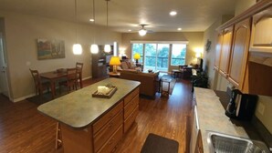 A spacious kitchen with wooden cabinets, a central island, pendant lighting, and a view to the outdoors. - Rogue River Guesthouse: Rural river views near I-5 (Gold Hill)