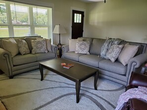 A living room with a grey sofa set, a coffee table, and a lamp.