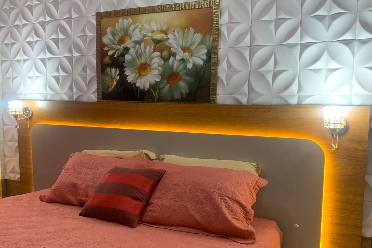 Una cama con cabecera, almohadas y una pared con un diseño geométrico.