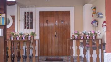 Una puerta de madera con diseños de corazones, un ventanal pequeño con rejas y un felpudo.