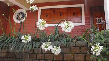 A brick wall with white flowers and a wooden door with heart-shaped cutouts.