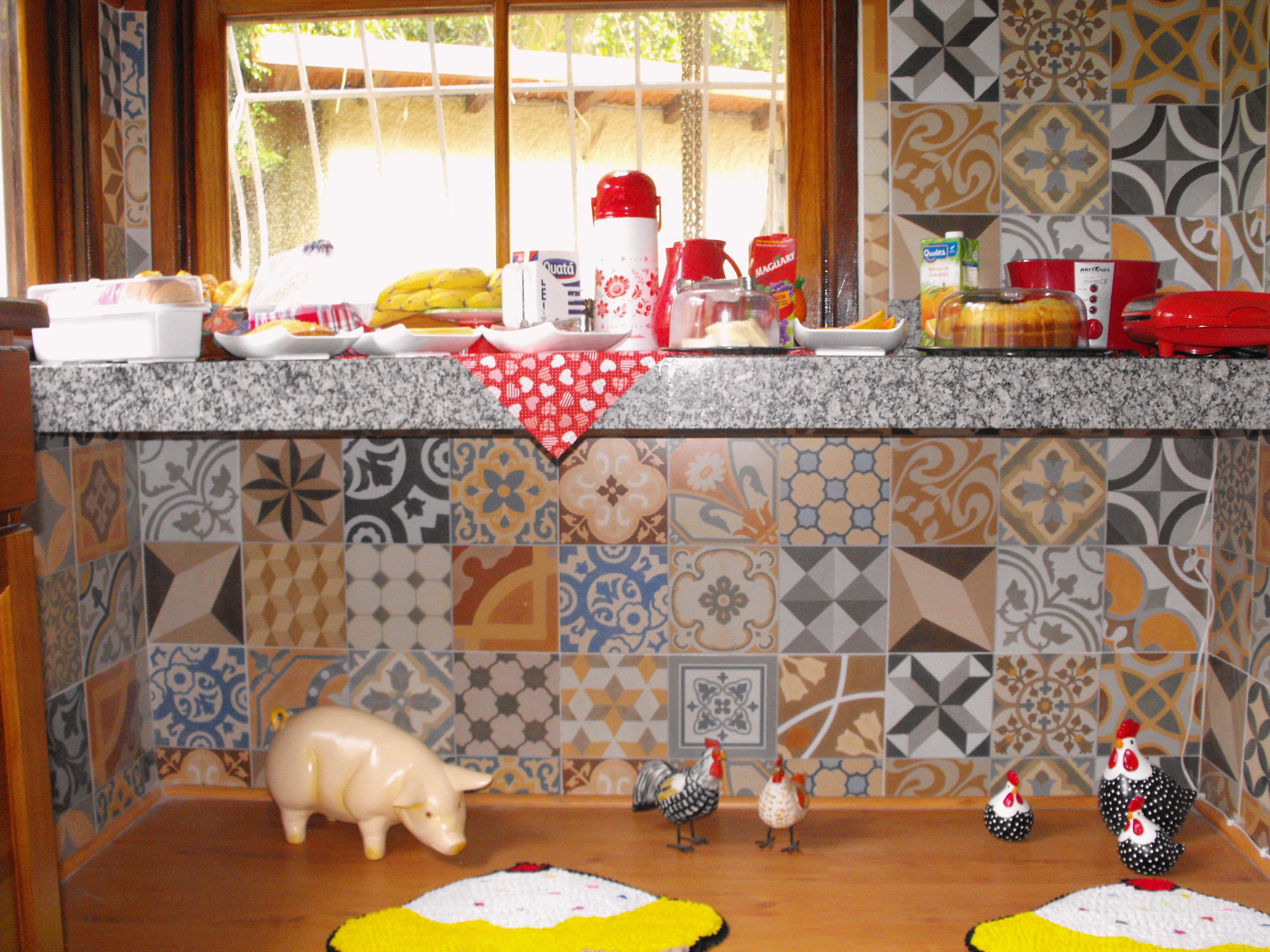 A kitchen with a tiled backsplash, a countertop with various items, and a pig figurine on the counter.
