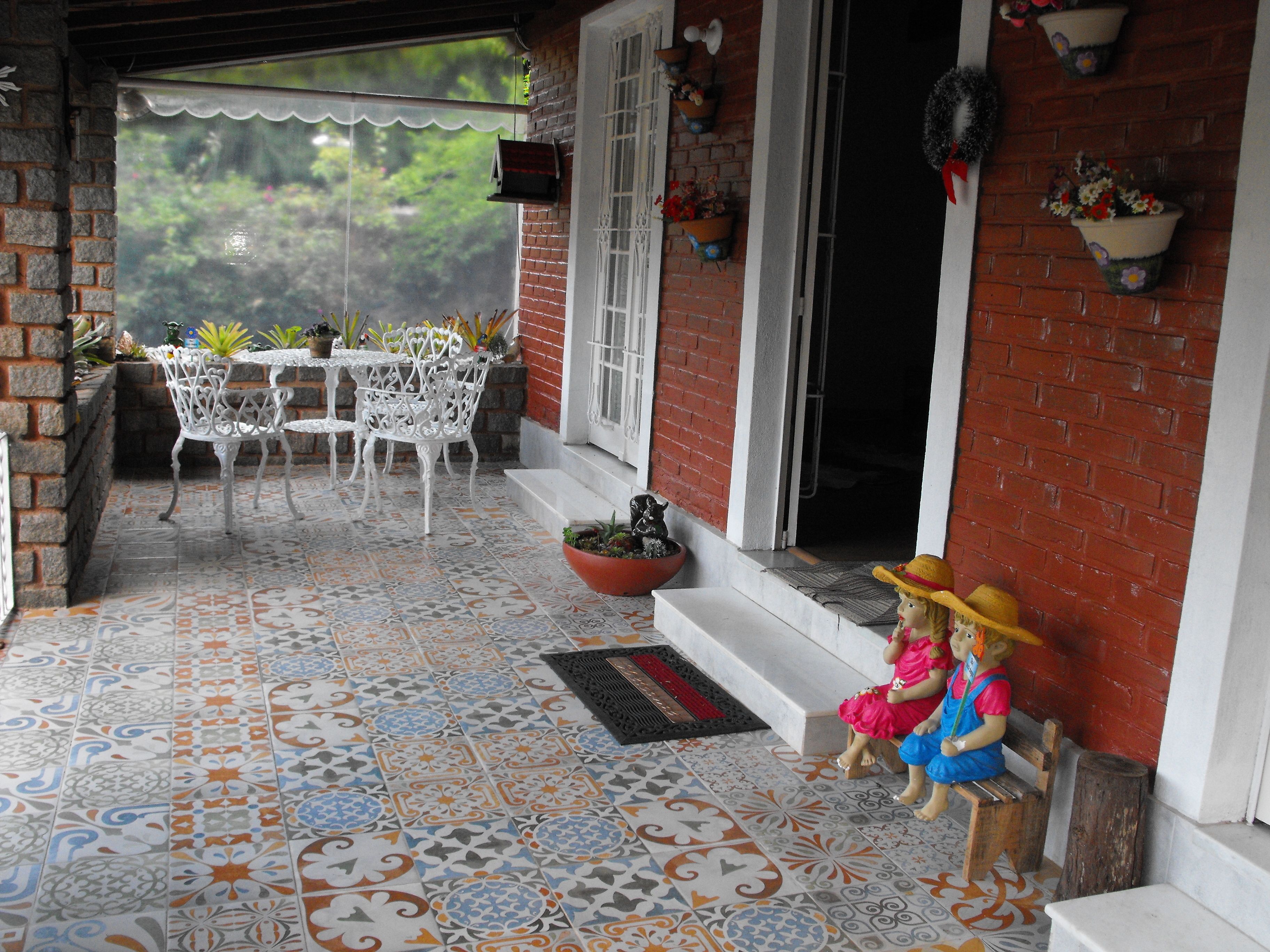 Un patio con baldosas estampadas, muebles de exterior blancos y plantas en macetas.