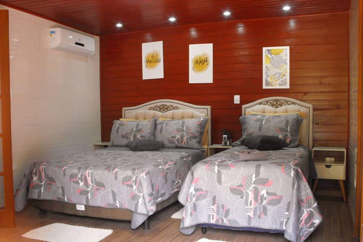Habitación de hotel con dos camas, paredes de paneles de madera e iluminación empotrada en el techo.