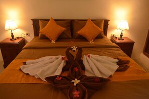 A bed with a brown headboard, two pillows, and a towel arrangement in the center. - The Rahayu Cottage (Penida Island)