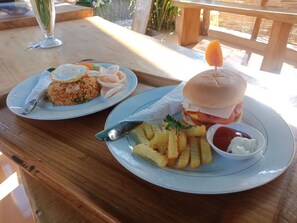 Two plates of food on a wooden table outdoors. - The Rahayu Cottage (Penida Island)