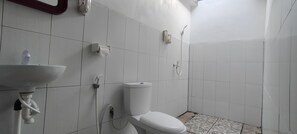 A small, white bathroom with a toilet, a sink, and a shower. - The Rahayu Cottage (Penida Island)