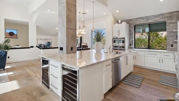 A modern kitchen with a central island, white cabinetry, stainless steel appliances, and pendant lighting. - Comfort in a Condo Gainey Ranch Style (Scottsdale)