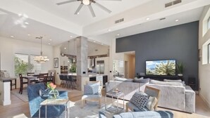 A spacious living area with a modern kitchen, a dining area, and a seating area with sofas and a coffee table. - Comfort in a Condo Gainey Ranch Style (Scottsdale)