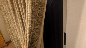 Pies de una persona sobre una alfombra, junto a una puerta con cortina.