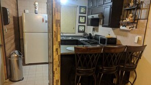 Una cocina con refrigerador, pileta y barra con taburetes.