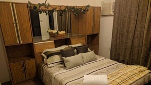Un dormitorio ordenado con cama, armario de madera y espejo sobre la cama.