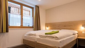 Une chambre d’hôtel moderne avec un lit en bois, une table de chevet et une fenêtre avec des rideaux.