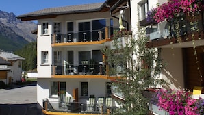 Un immeuble à deux étages doté de balcons, de grandes fenêtres et surplombant un paysage montagneux.