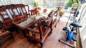 A traditional wooden dining set with a glass-top table, surrounded by ornate chairs, in a room with a view of a balcony. - Forget Me Not Hotel Nha Trang (Nha Trang)