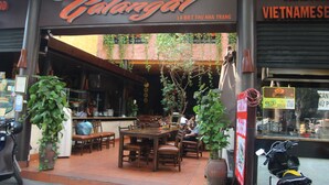 An outdoor dining area with wooden tables and chairs, surrounded by potted plants. - Forget Me Not Hotel Nha Trang (Nha Trang)
