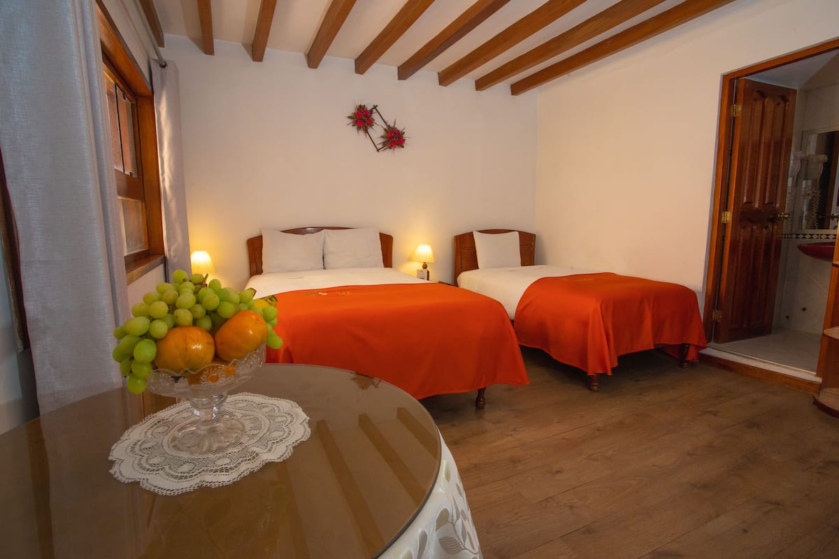 Ein Hotelzimmer mit zwei Betten, einer Holzbalkendecke und einem Tisch mit Obst.
