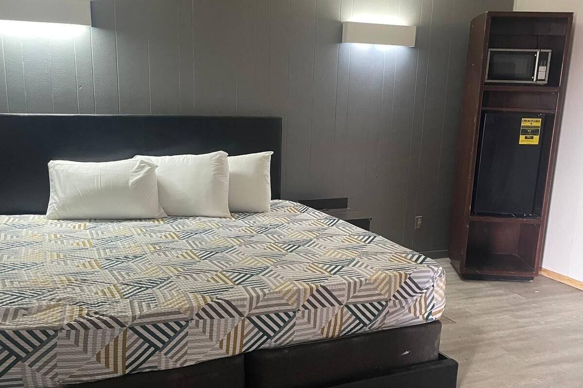 A bedroom with a large bed, dark headboard, and two wall-mounted lights.