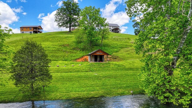 A serene lakeside property with a small cabin and a larger house on a grassy hill. - Ruth's Retreat on South Holston River  (Bristol)