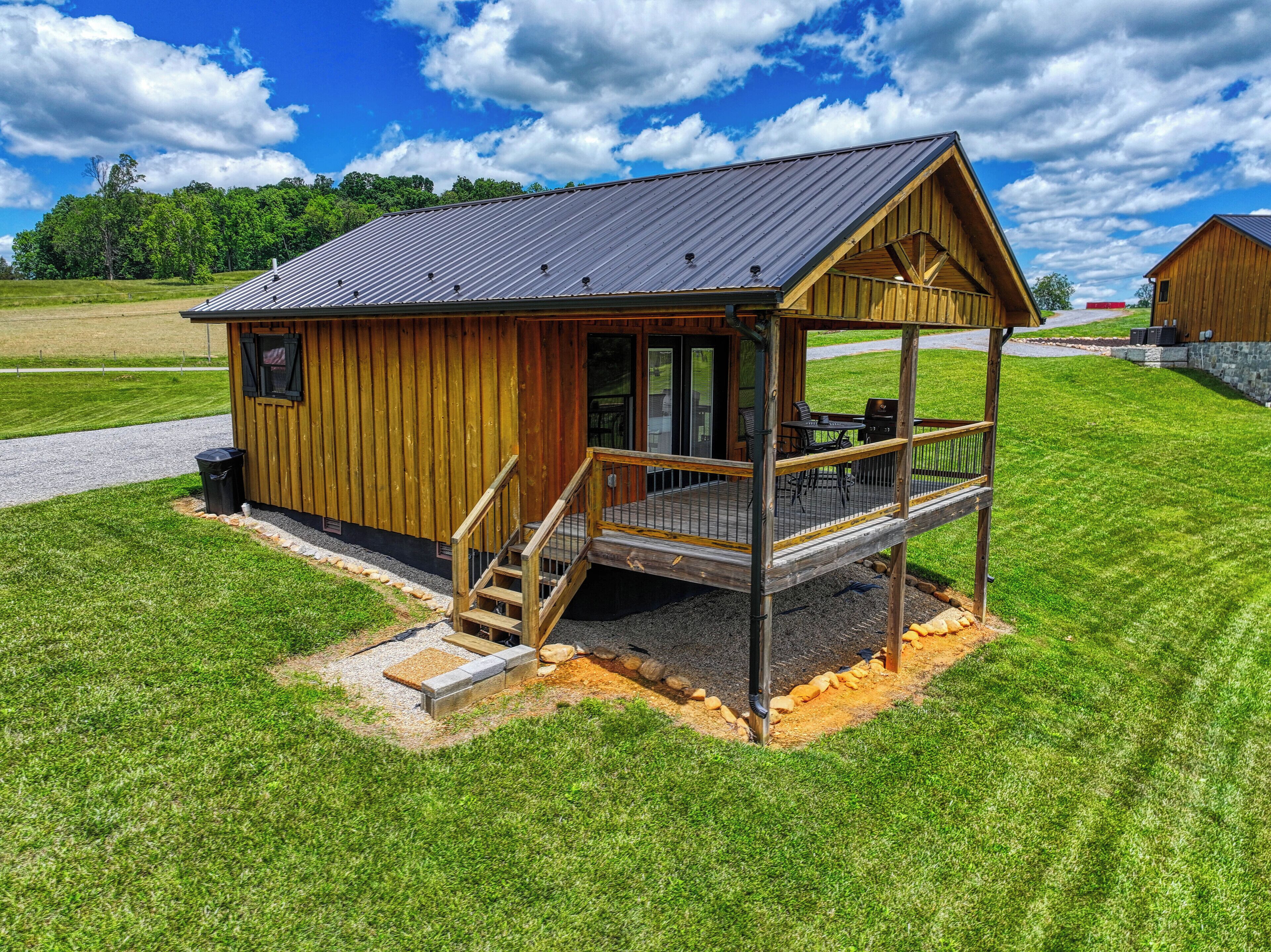 A wooden cabin with a porch, a staircase, and a gravel driveway.